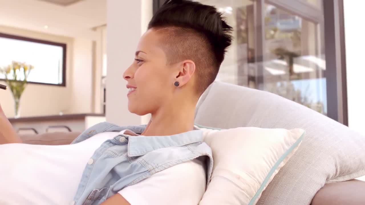 행복 한 임신 한 여자 는 소파 에 앉아 노트 패드 에 글 을 쓰고 있다