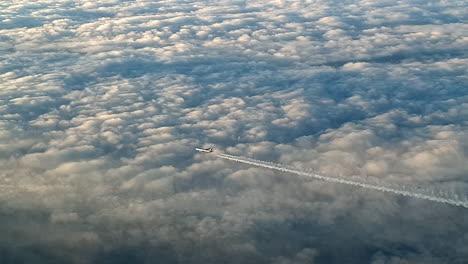 Vista-Increíble-Desde-La-Cabina-De-Un-Avión-Que-Vuela-Alto-Por-Encima-De-Las-Nubes-Dejando-Un-Largo-Rastro-De-Aire-De-Vapor-De-Condensación-Blanco-En-El-Cielo-Azul