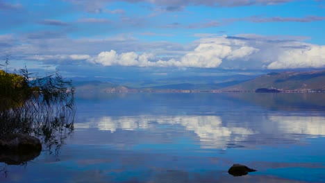 beautiful lake panorama with calm water reflecting clouds and mountains at twilight in pogradec