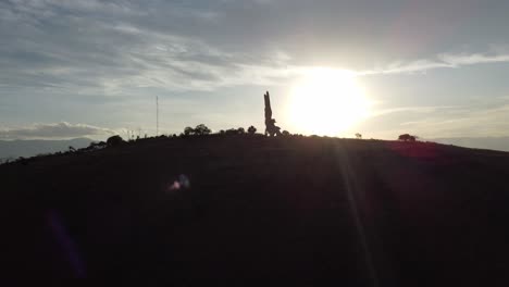 sunset of a mountain with a contrasting sculpture of an angel