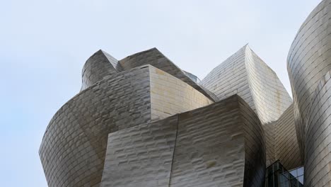 Stainless steel waves of the Guggenheim Bilbao reflect light and sky, a testament to Gehry’s deconstructivist vision in Bilbao, Spain.