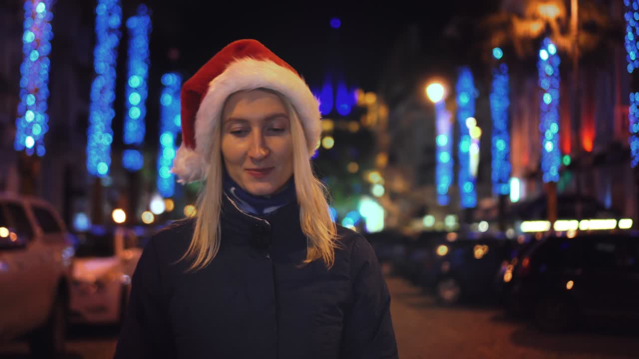 산타클로스 모자를 입은 아름다운 여성이 크리스마스 밤에 고 있습니다.