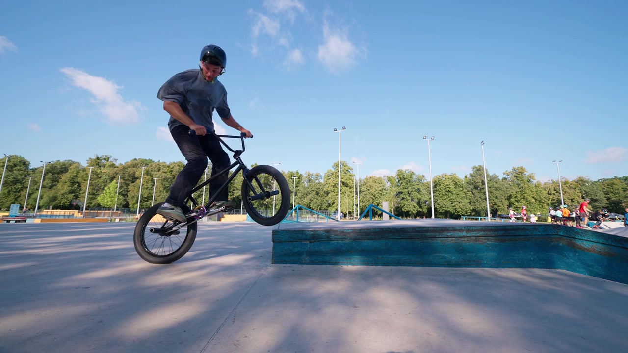 Abile ciclista BMX che esegue un trick in uno skatepark soleggiato