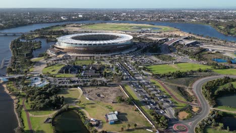 aerial approaching shot of optus stadium with swan river during sunset time in perth city, western australia