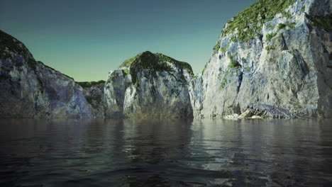 Rocky cliffs reflect in calm water at twilight near the coastal shore