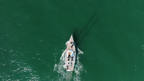 aerial establishing view of a white sailboat in the calm batltic sea, white sailing yacht in the middle of the boundless sea, sunny summer day, wide birdseye done tracking shot moving forward
