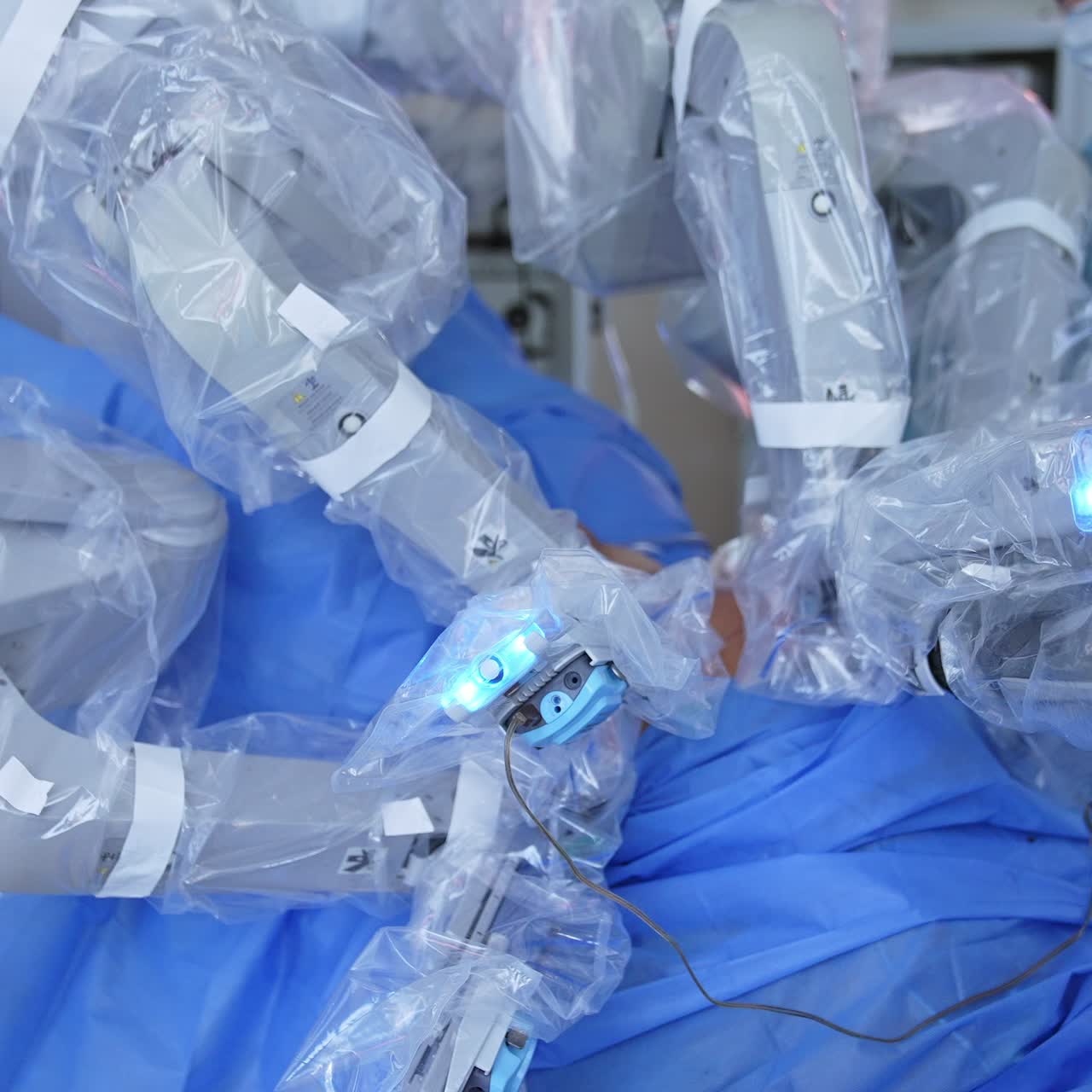 Robotic arms move slowly and carefully over the patient. Doctor and assistant standing in blur at backdrop