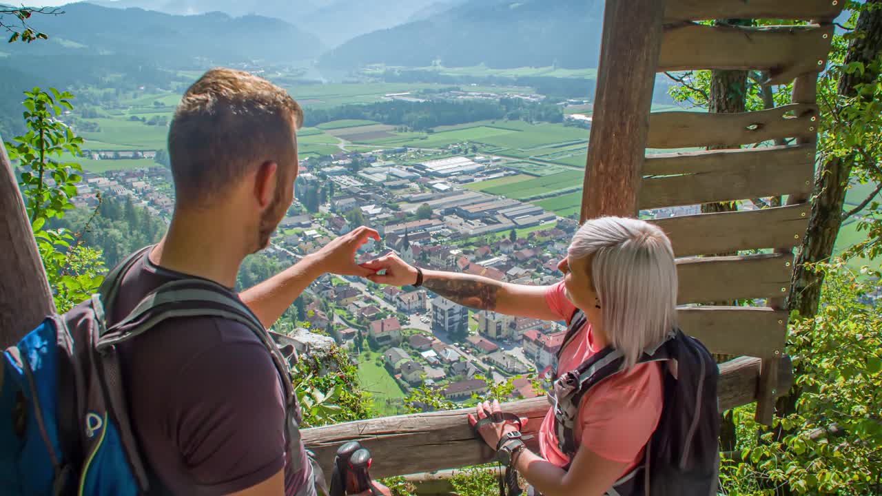 Couple makes a heart with their hands. Overlooking beautiful scenery in the background. Green window, Slovenia