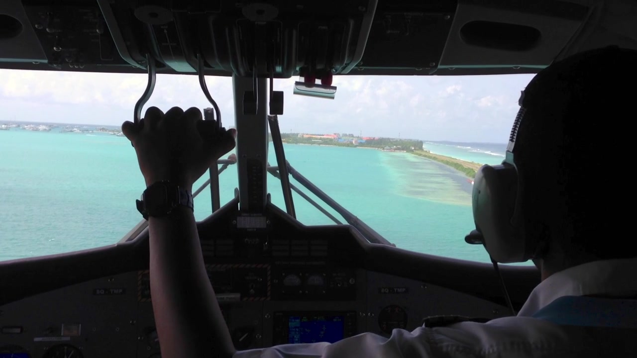 Cockpit view of pilot landing a seaplane on tropical water