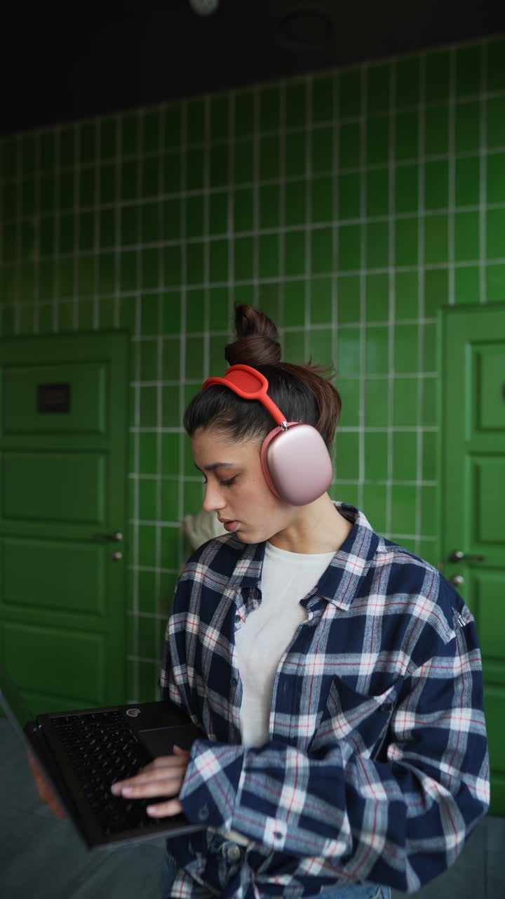 mujer joven trabajando en una computadora portátil con auriculares