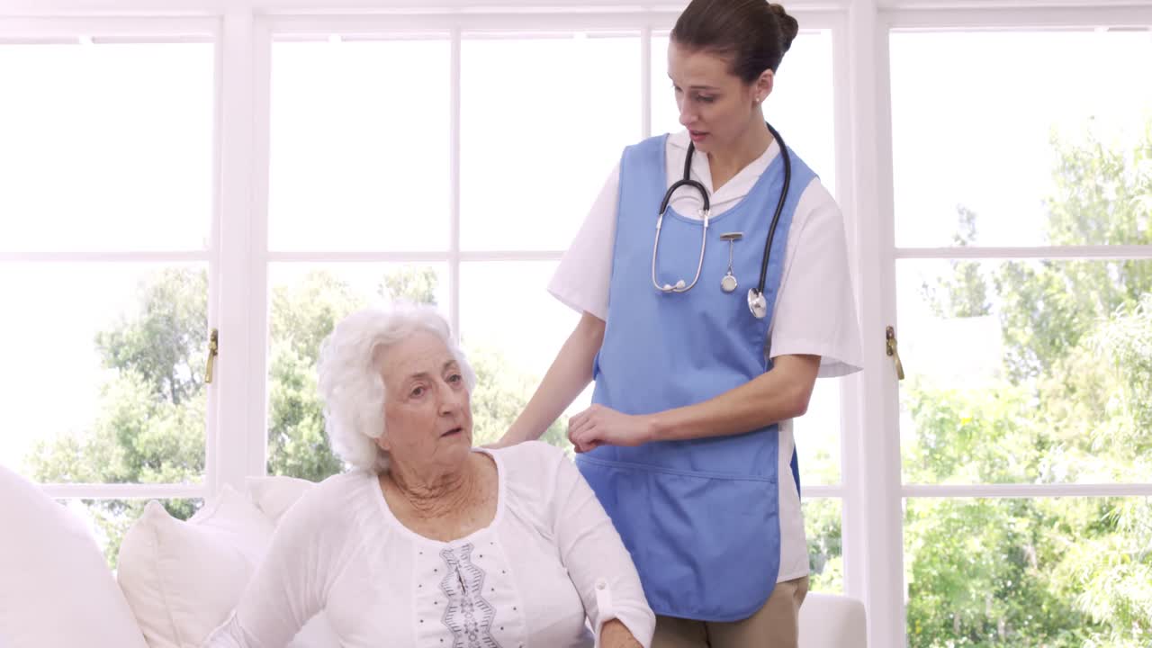 Fröhliche Krankenschwester im Gespräch mit Seniorin
