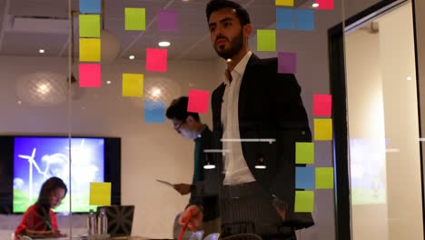 hombre de negocios mirando notas adhesivas en la oficina 4k