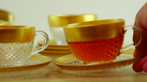 a serene moment as a hand gently places a glass of deliciously brewed tea onto a table