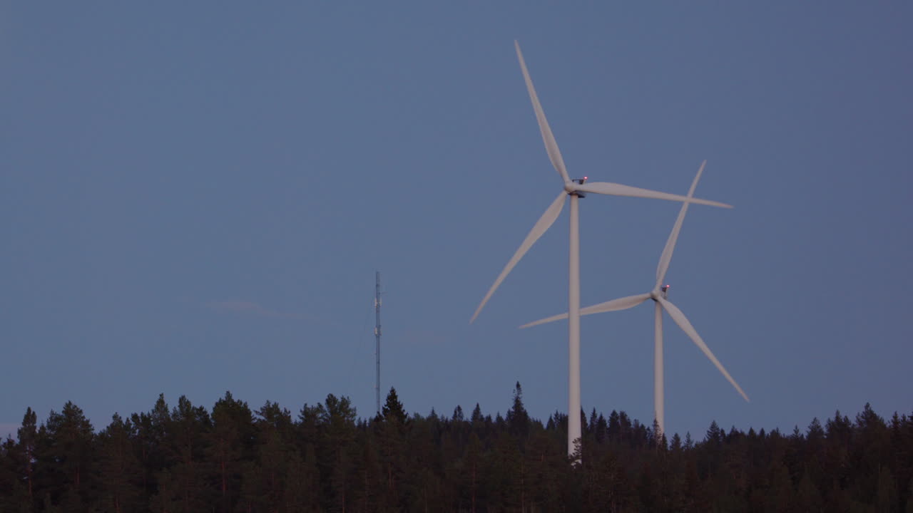 SLOW MOTION, ZOOM IN - Wind turbines spin next to a rising full moon