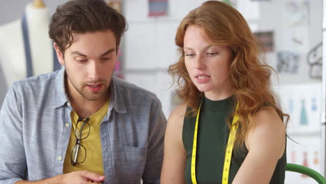 male and female clothes designers looking at sketches and working on designs in fashion studio