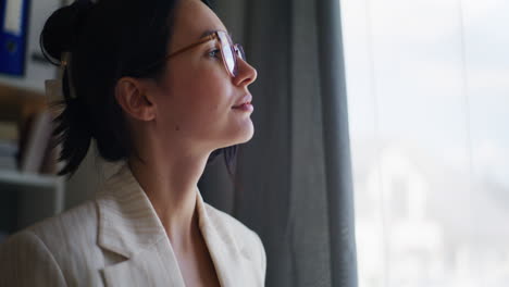 una mujer de negocios pensativa buscando inspiración por la ventana.