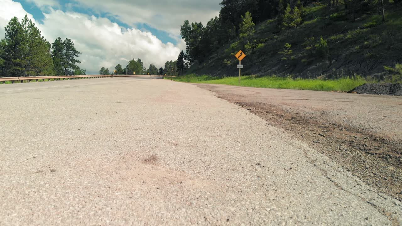 Beautiful landscape with a mountain road going straight into the clouds. Mountain road. Landscape with rocks, sunlight through a tree and an asphalt road in the summer. Background travel.
