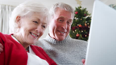 una pareja de mayores haciendo una llamada de video de navidad a la familia en la computadora portátil