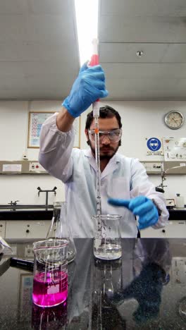 chemist holding a beaker and pipette during testing