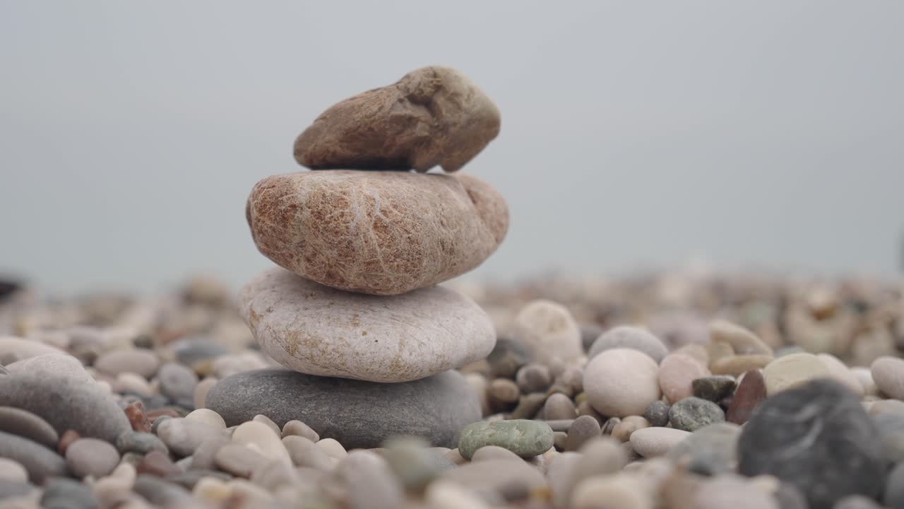 Hands Stacking Stones on a Pebble Beach