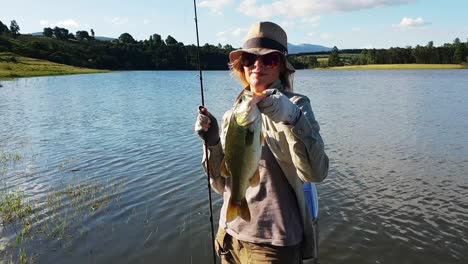 a girl holding a fish she caught from a boat on a calm beautiful lake