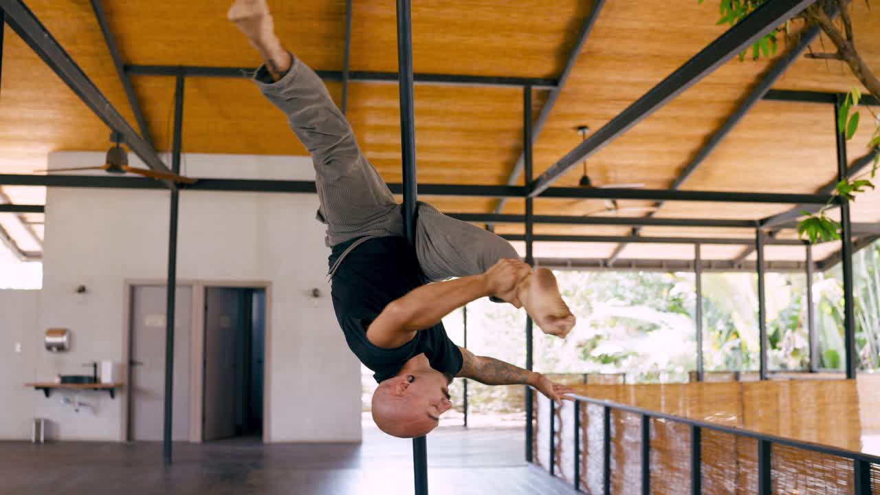Man Performing Aerial Pole Dance Acrobatics in a Bright Studio