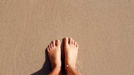 Top-view,-beach-and-person-feet-in-waves