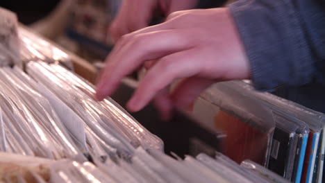 close-up of hands sorting through records at a record shop