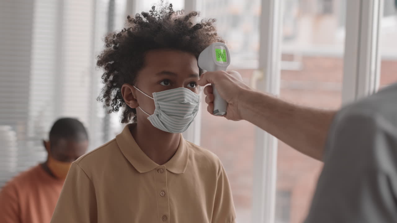 niño africano comprobando la temperatura corporal