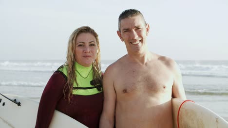una pareja de surfistas sonriendo a la cámara