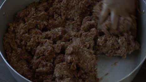 mince meat in large casserole pan being kneaded by one hand