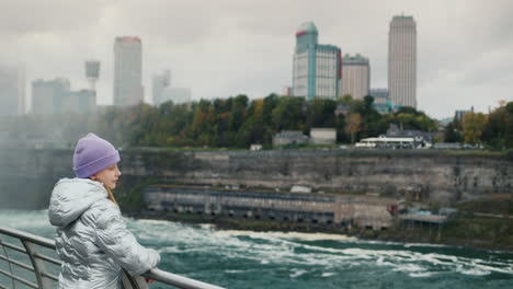 The-child-admires-the-Niagara-River-and-the-waterfall,-stands-against-the-background-of-the-Canadian-coast