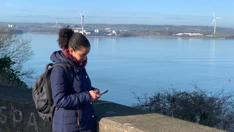 a young woman is playing on her phone, ocean background