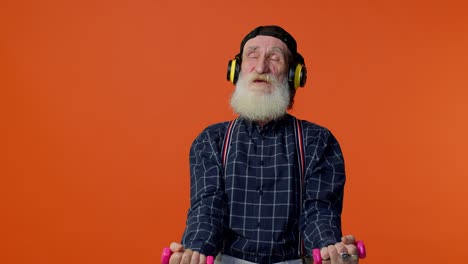 Elderly-bearded-man-listening-music-via-headphones,-working-out,-lifting-pink-dumbbells,-healthcare