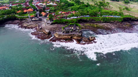 tanah lot temple on coastal rock formation in bali in sea waves