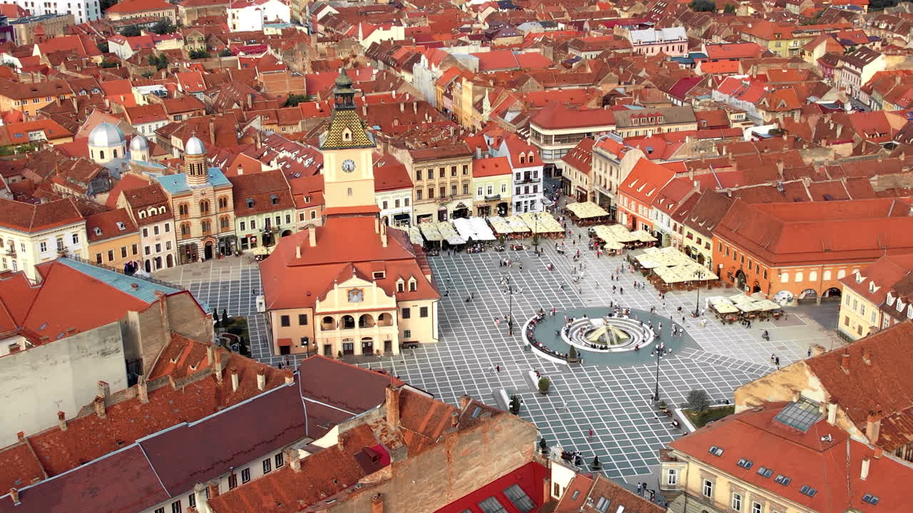 Lotniczy widok z drona na główny plac w Braszowie nocą, Rumunia. Stare centrum miasta z Muzeum Historycznym, Czarnym Kościołem, budynkami, nocnymi światłami, ludźmi