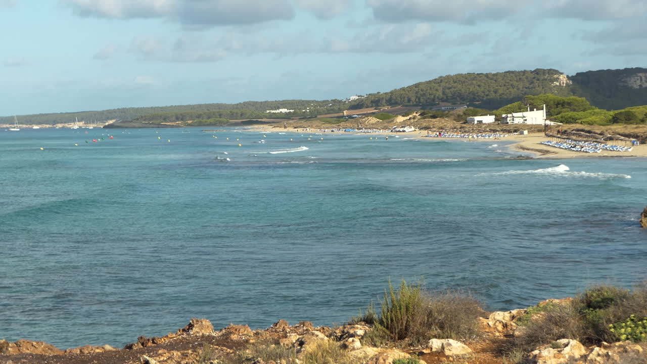 Veduta panoramica della spiaggia di Son Bou, la più lunga di Minorca, onde regolari sul mare con barche, Isole Baleari, Spagna