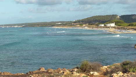 Vista-Panorámica-De-La-Playa-De-Son-Bou,-La-Más-Larga-De-Menorca,-Olas-Regulares-En-El-Mar-Con-Barcos,-Islas-Baleares,-España