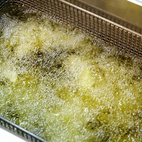french fries in the deep fryer. fast food restaurant, cooking potato, crispy fries. junk food concept. top view video. close up