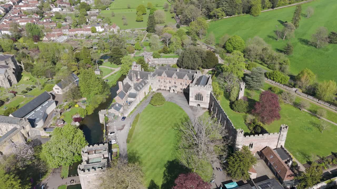 Aerial view of historic bishop’s palace estate featuring crenellated stone walls, towers, and manicured gardens surrounded by ancient trees, embodying heritage architecture and tranquillity