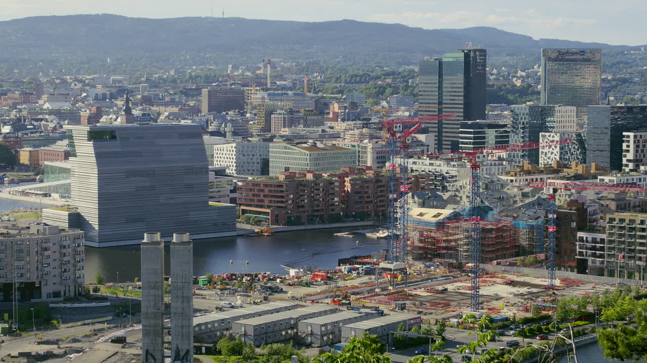 A city view featuring skyscrapers, cranes, modern buildings, and a waterfront under development. Bjørvika in Oslo under construction.