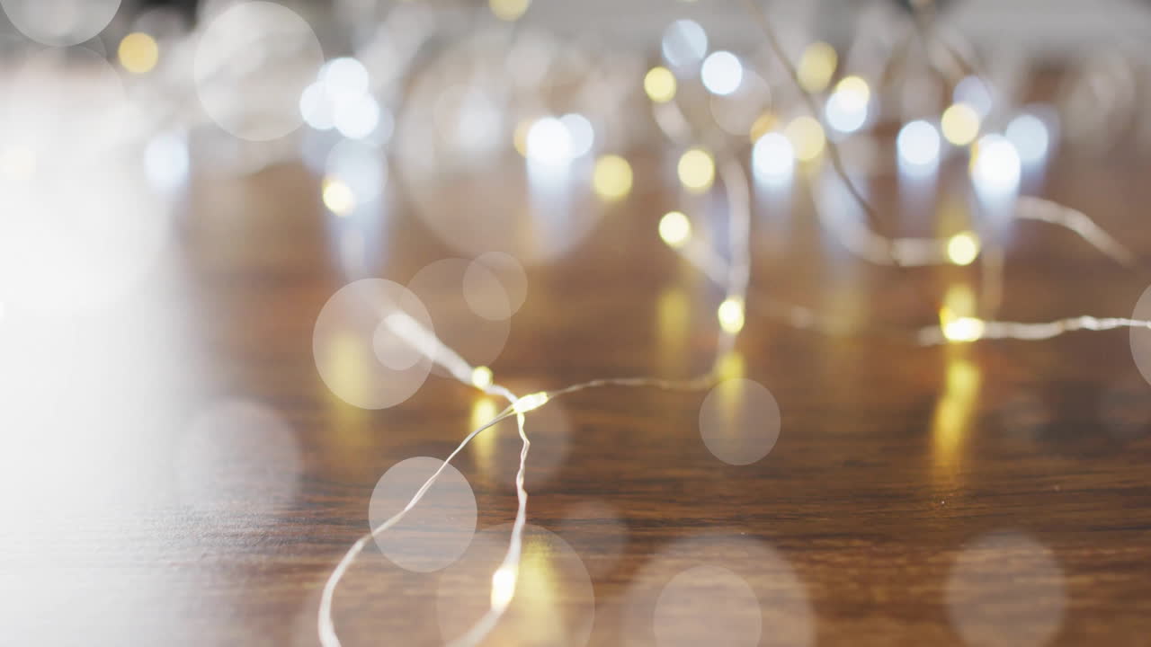 Bokeh lights animation over blurred string lights on wooden surface