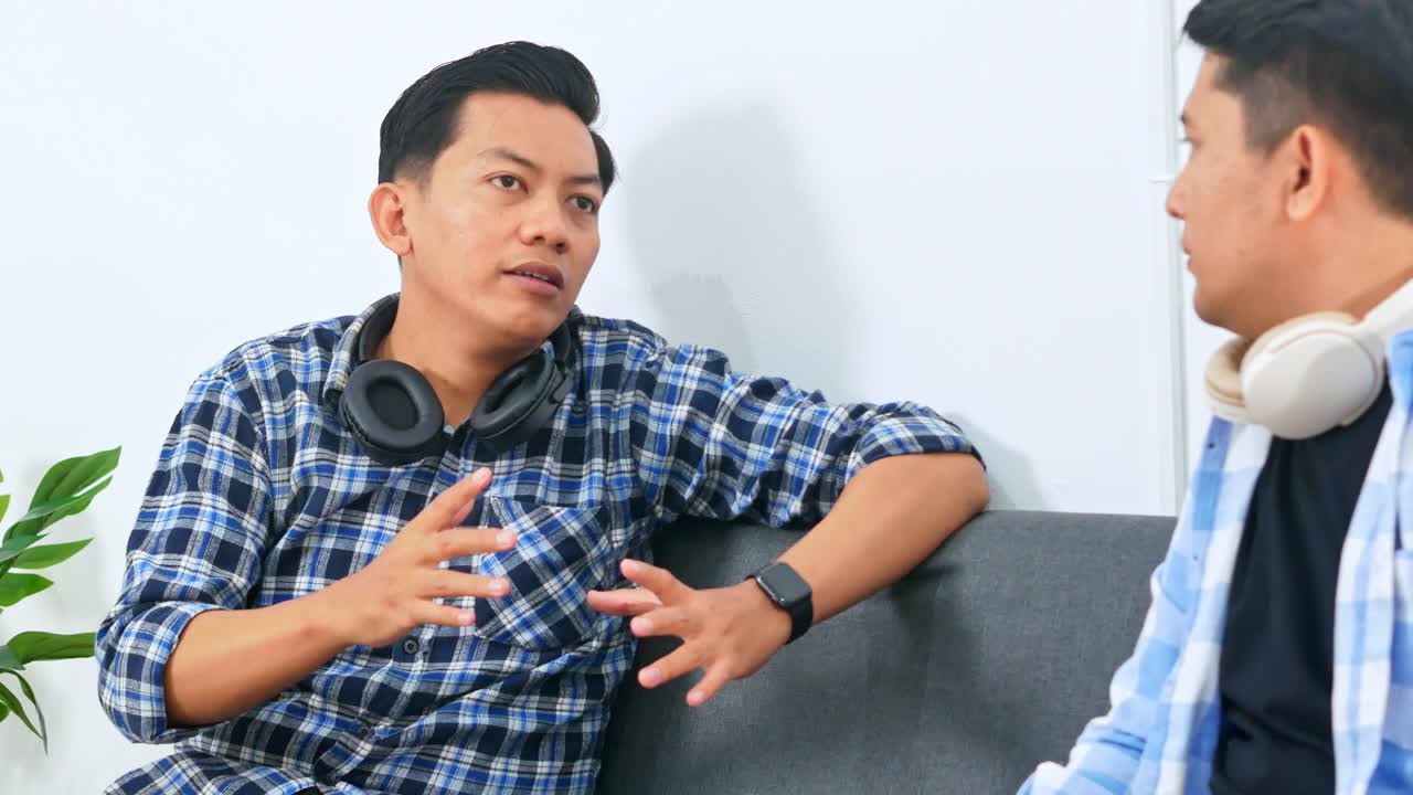 Two workers asian men in casual conversation on sofa