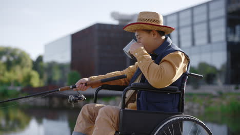 man in wheelchair fishing and drinking