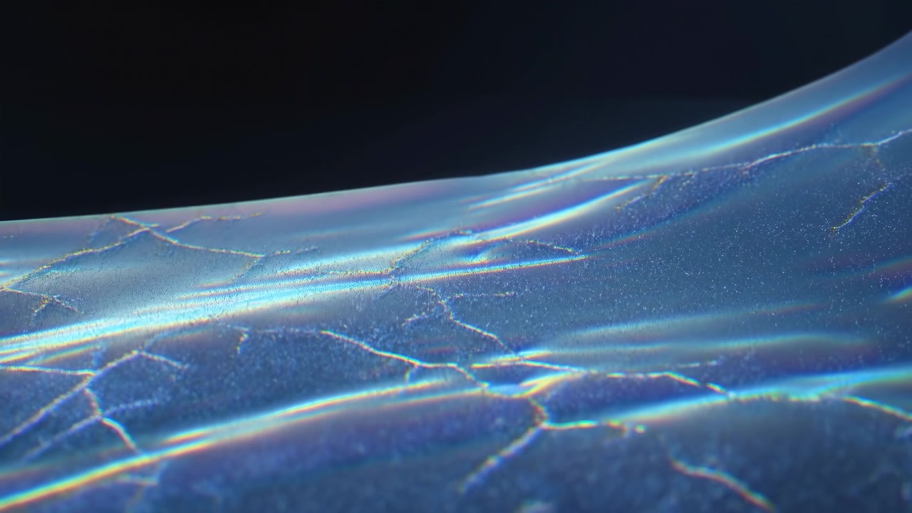 Nahaufnahme einer glänzenden, irisierenden Oberfläche, die sichtbar von glatten horizontalen Wellen in feine Kratzer und verzweigte Bruchlinien übergeht, mit weichem gerichteten Licht, wechselnden Reflexionen und