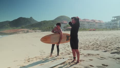 two men on a sunny beach preparing to surf with their surfboards