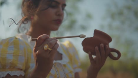 Hispanic-woman-gently-brushing-old-ceramic-teapot,-slow-motion-closeup-of-hands-gold-ring