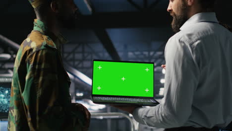 army tech specialist in data center and coworkers using green screen laptop