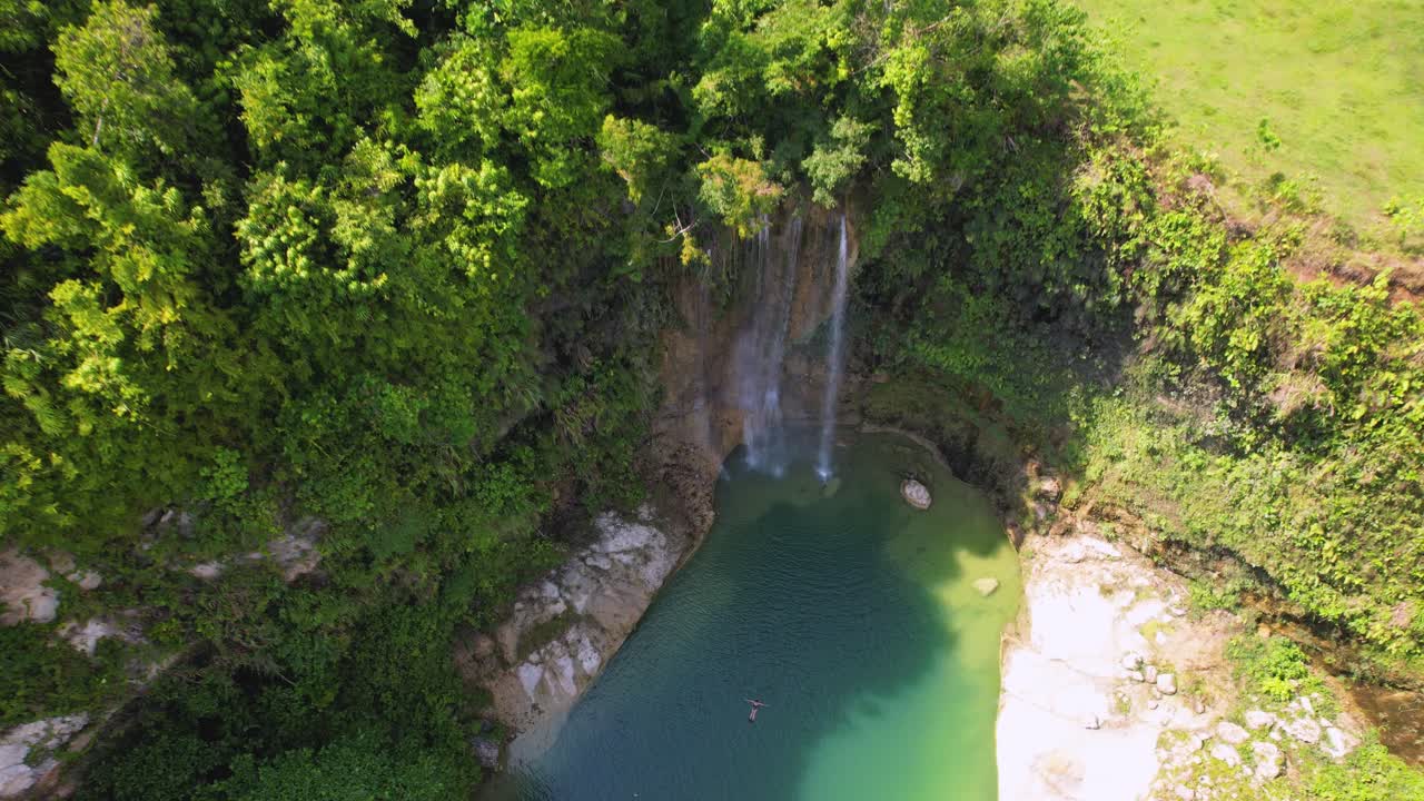 Video drone 4K che vola verso una donna che nuota alle Cascate di Camugao a Bohol, Filippine