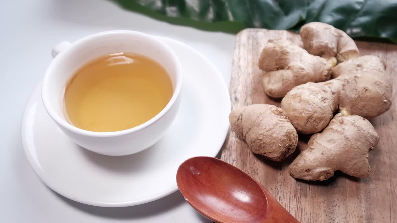 té de jengibre en una taza blanca con raíces de jengubre frescas
